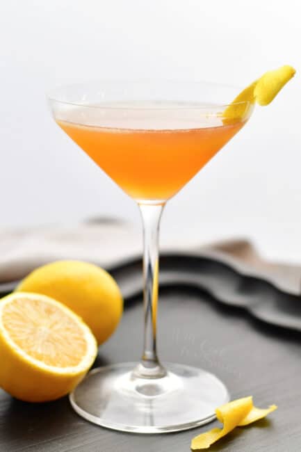 side view of a tall martini glass with orange colored Sidecar cocktail