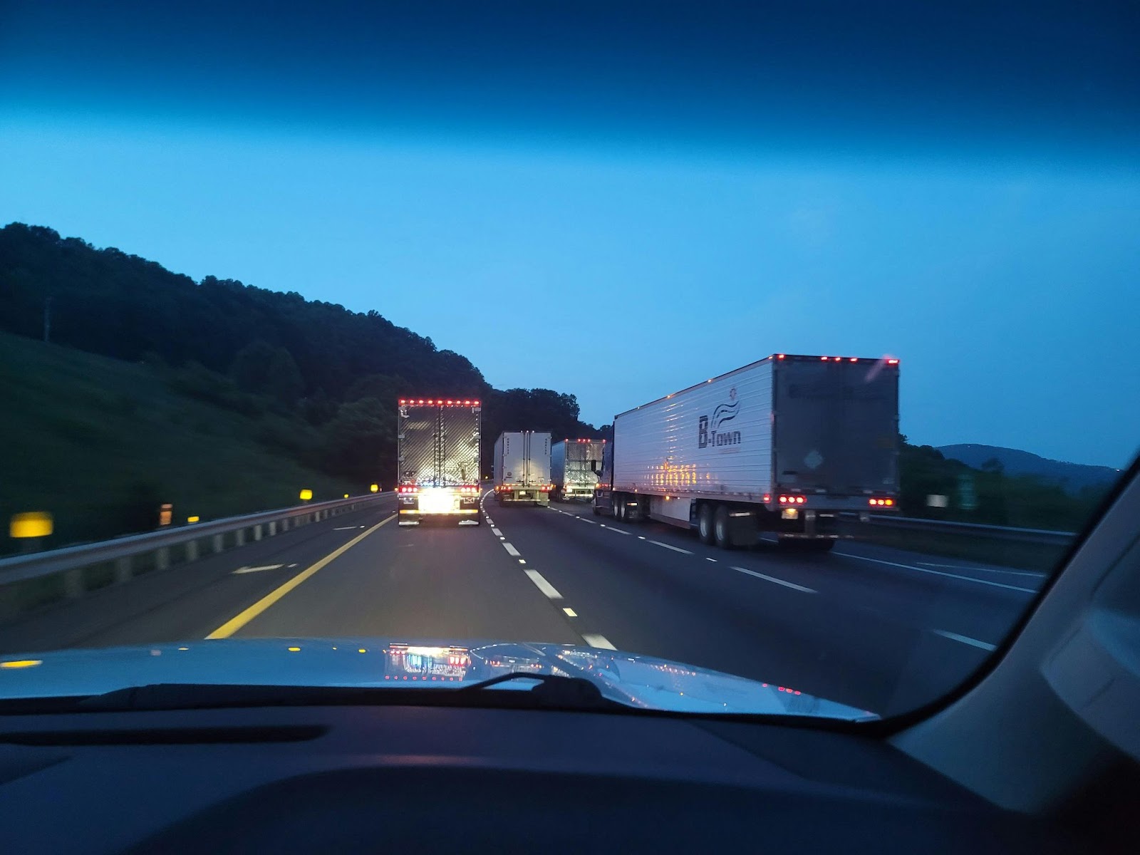 Vista desde el interior de un vehículo en una carretera con cuatro camiones grandes, destacando la optimización de rutas de entrega.