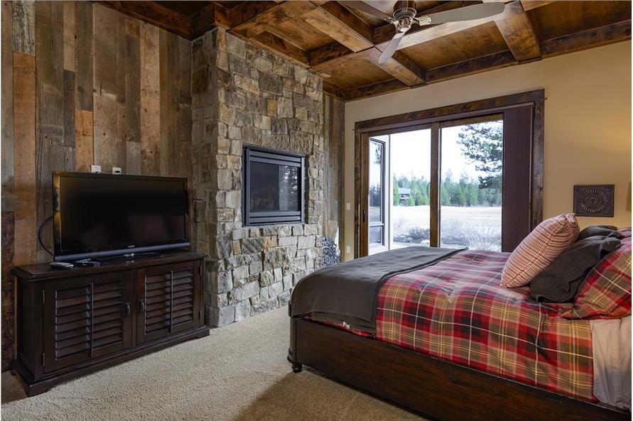 The primary bedroom includes a TV and a glass-enclosed fireplace fitted on the stone accent wall.