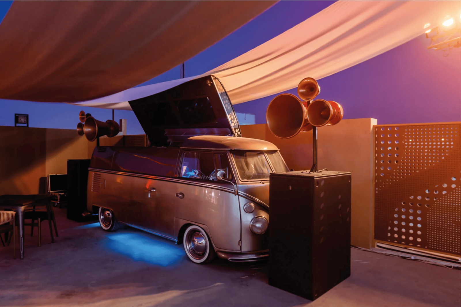 Unique wedding venue feature with a retro-style DJ van, ambient lighting, and shaded setup.