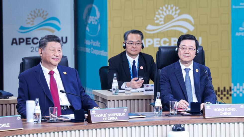 李家超(圖右)在APEC會議期間，坐在中國國家主席習近平(圖左)旁邊，間中有交談，未知有否得連任啟示。