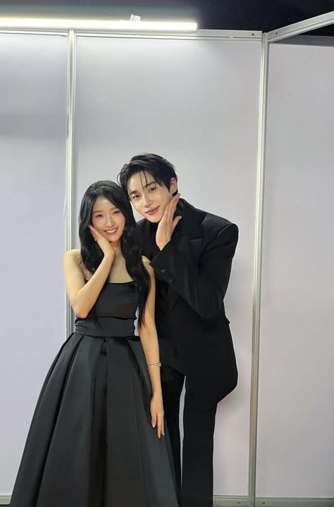 This contain Byeon Woo Seok and Kim Hye Yoon standing next to each other in front of a white wall and posing for the camera