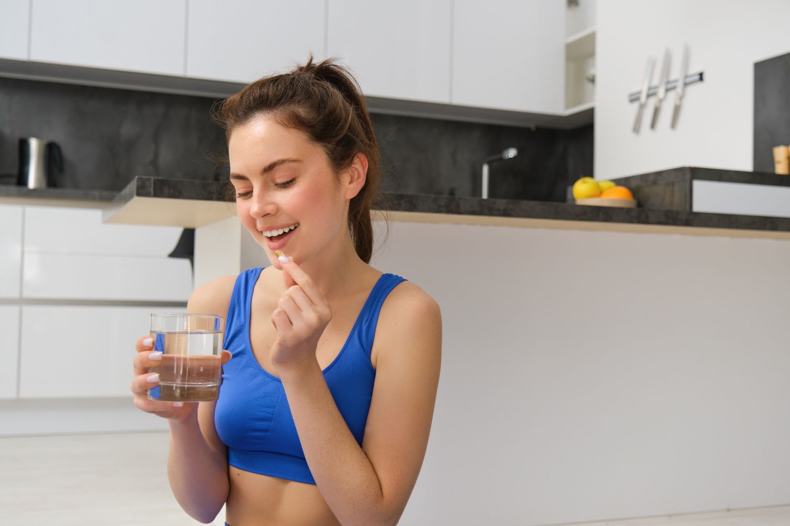 Portrait healthy smiling woman drinking a glass of water that is natural ways to improve gut health.