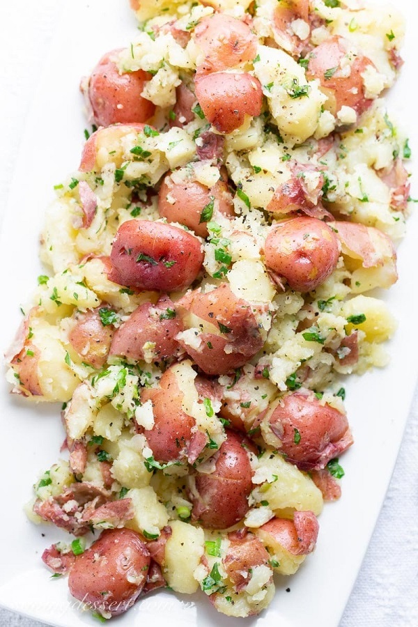 Garlic herb smashed red potatoes on a white serving platter