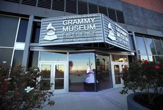 This contains an image of the Grammy museum is lit up at night with lights shining on it's windows