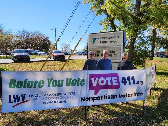 A group of people standing in front of a sign

Description automatically generated