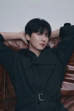 This contain a picture of Kim Nam Gil sitting on top of a brown leather couch with his arms behind his head