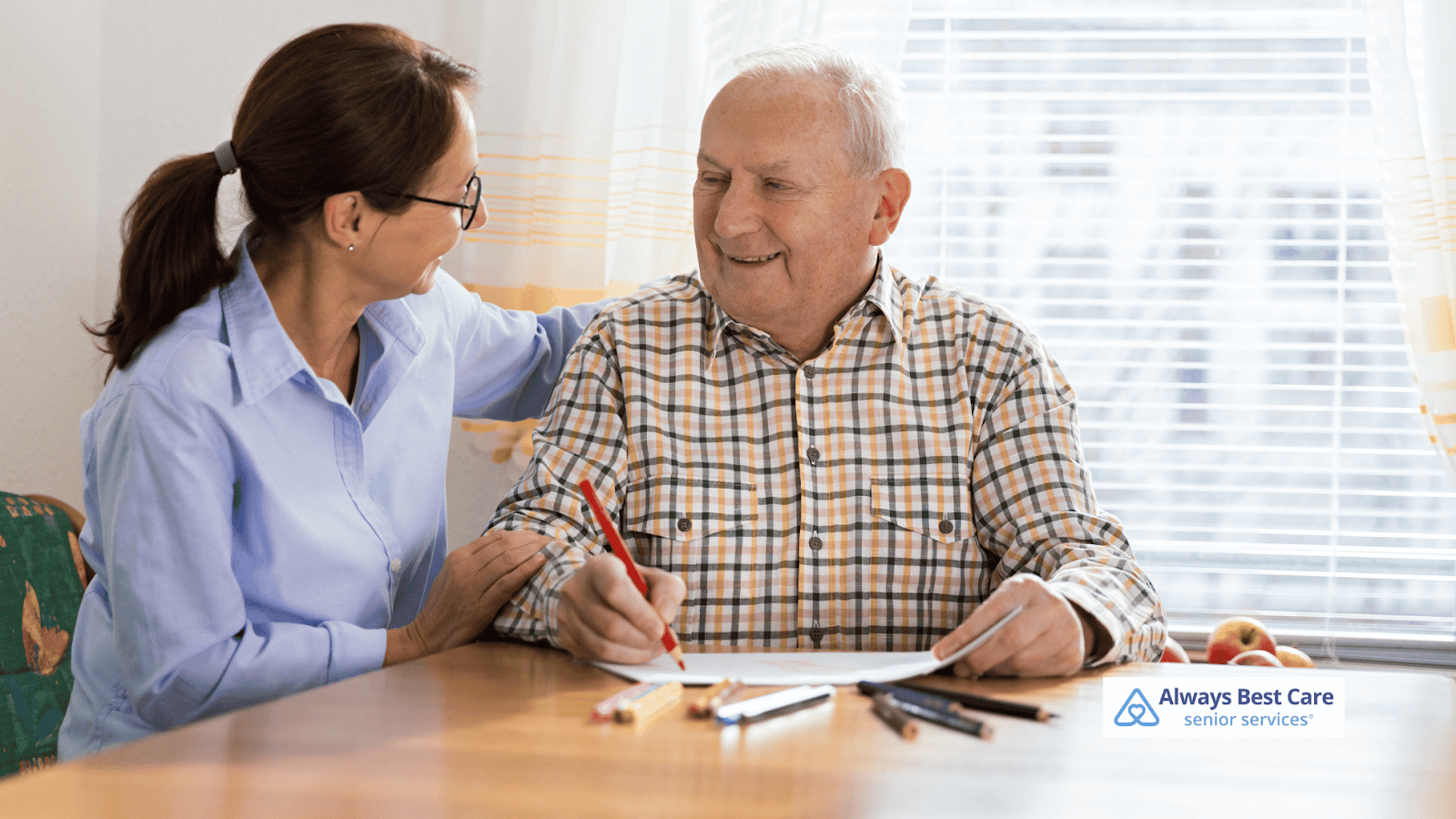 This image depicts an Always Best Care caregiver helping a senior man with memory issues handle paperwork