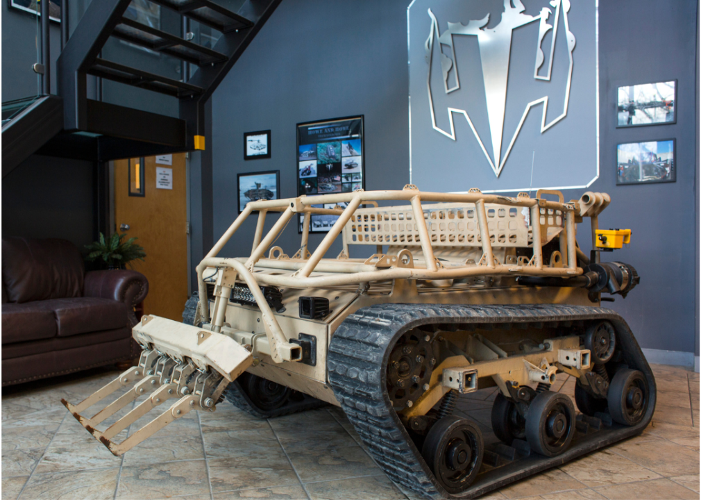 A relatively small military tank robot on display in a building.