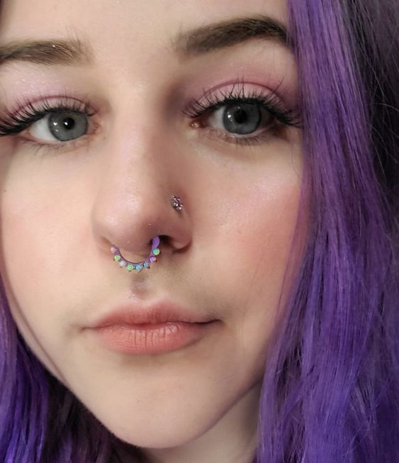 A gril with purple hair wearing a glittery septum piercing