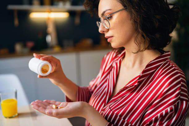 A woman taking a probiotic supplement in a bright, airy setting.