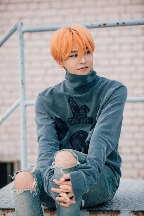 This contains an image of G-Dragon with a orange hair sitting on top of a metal rail