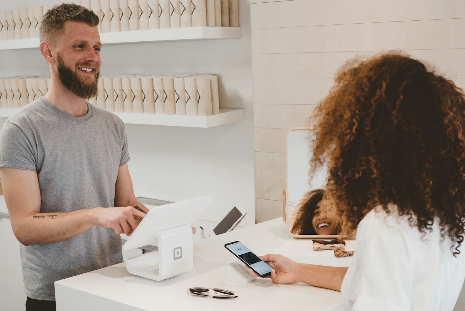 A man and woman smile as they stand together in front of a cash register, ready to make a purchase.