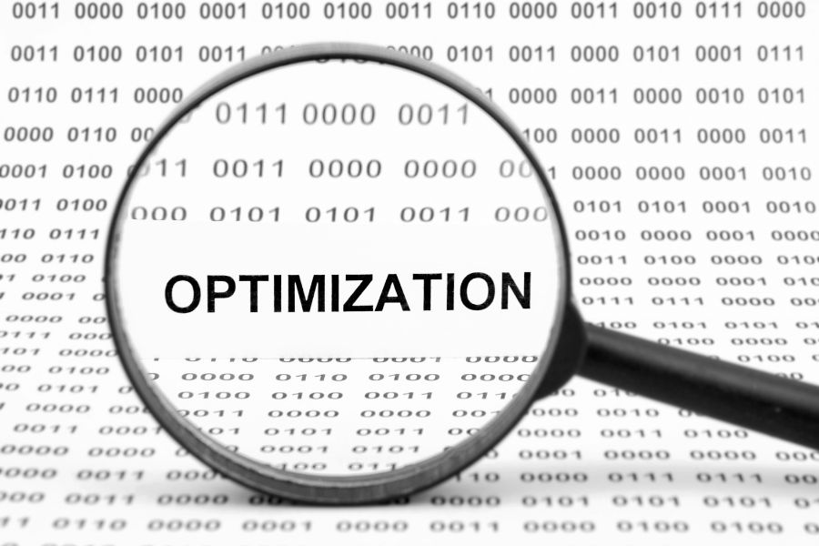 Magnifying glass focusing on the word "Optimization" over binary code background.