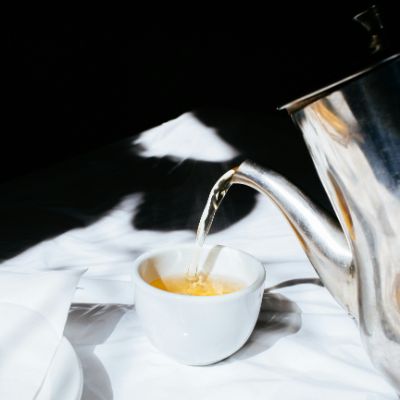 A tea being poured through a tea pot.