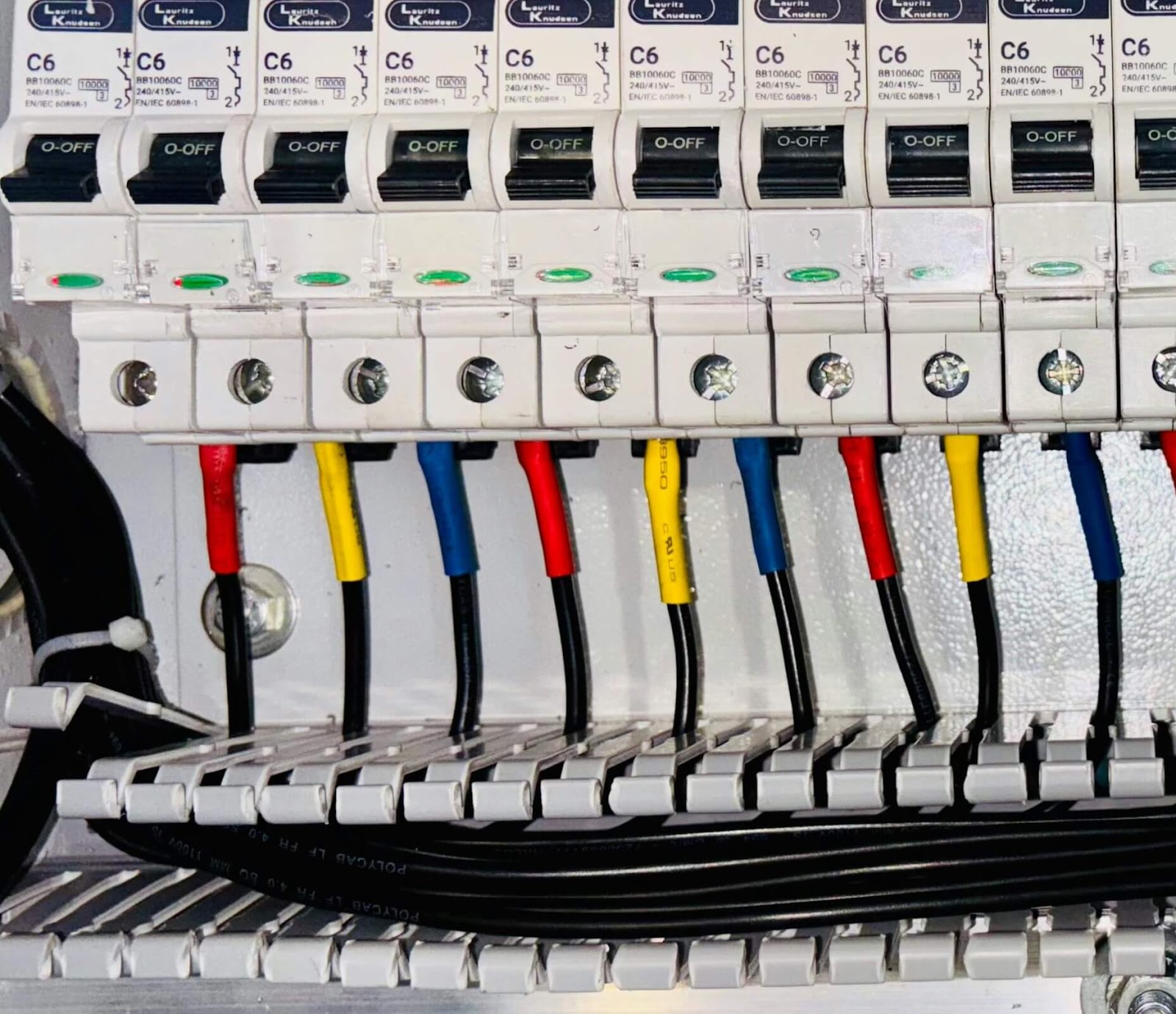 The inside of an electrical panel with red, yellow, and blue wires.