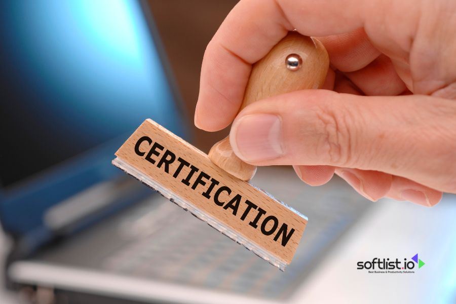 Hand holding a certification stamp in front of a laptop