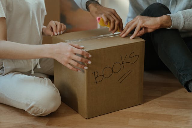 Two people opening a box labeled books