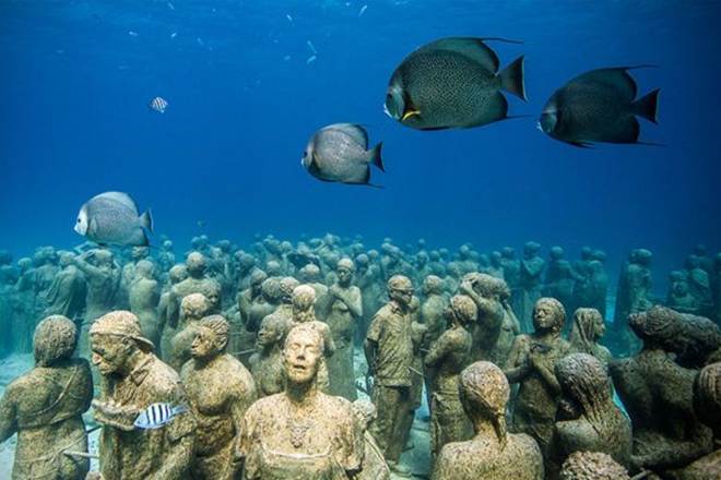 This may contain: some statues are under the water with fish around them