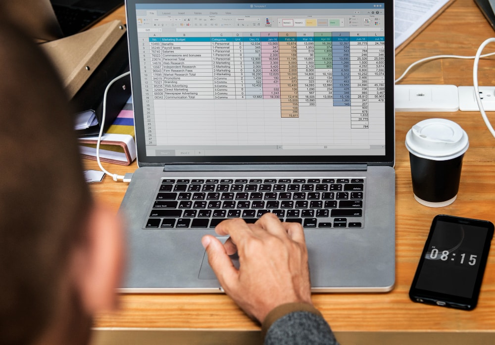 A business owner is infront of a laptop displaying a smart spreadsheet, highlighting the benefits of automated billing.