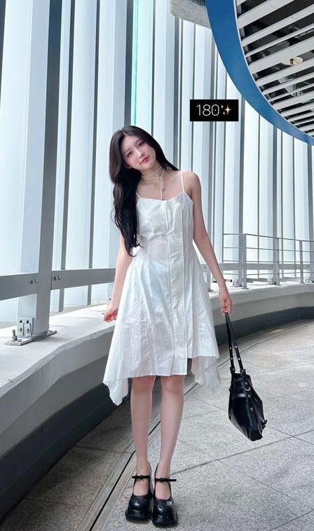 This  contain an image of  MADEIN Gaeun's  in a white dress holding a black purse