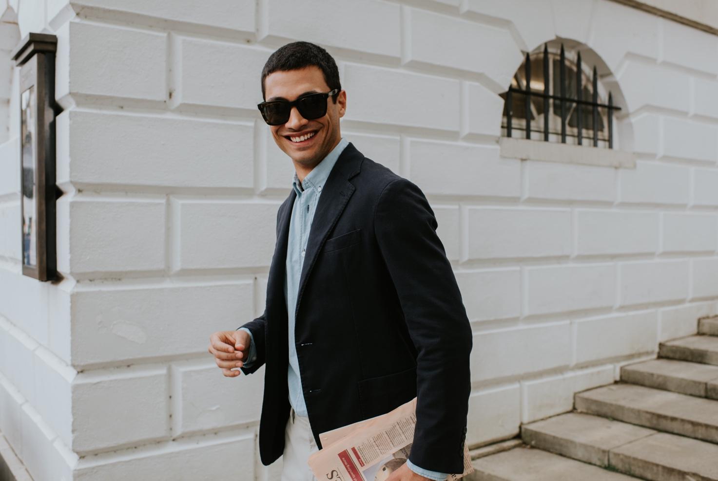 A person in a suit and sunglasses walking down a stairs Description automatically generated