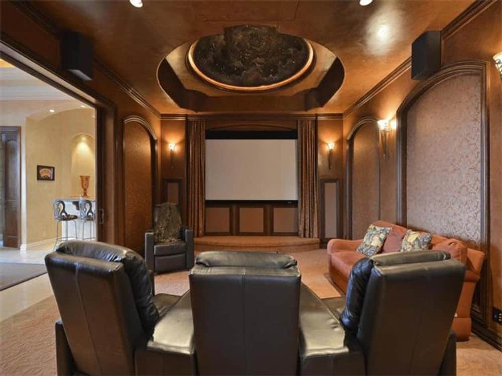 Media room with black recliners, a terracotta sofa, and a dome ceiling graced with intricate detailing.