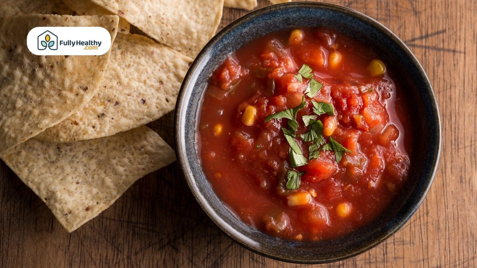 Bowl of chunky salsa with corn and tortilla chips beside it
