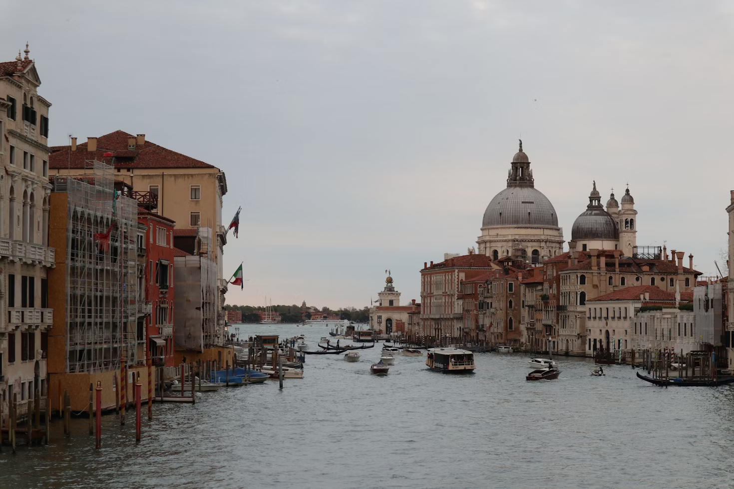 曇り空の下、イタリアのヴェネツィアにあるグランドキャナルの景色。歴史的な建物と象徴的なサンタ・マリア・デッラ・サルーテ聖堂のドームが特徴。