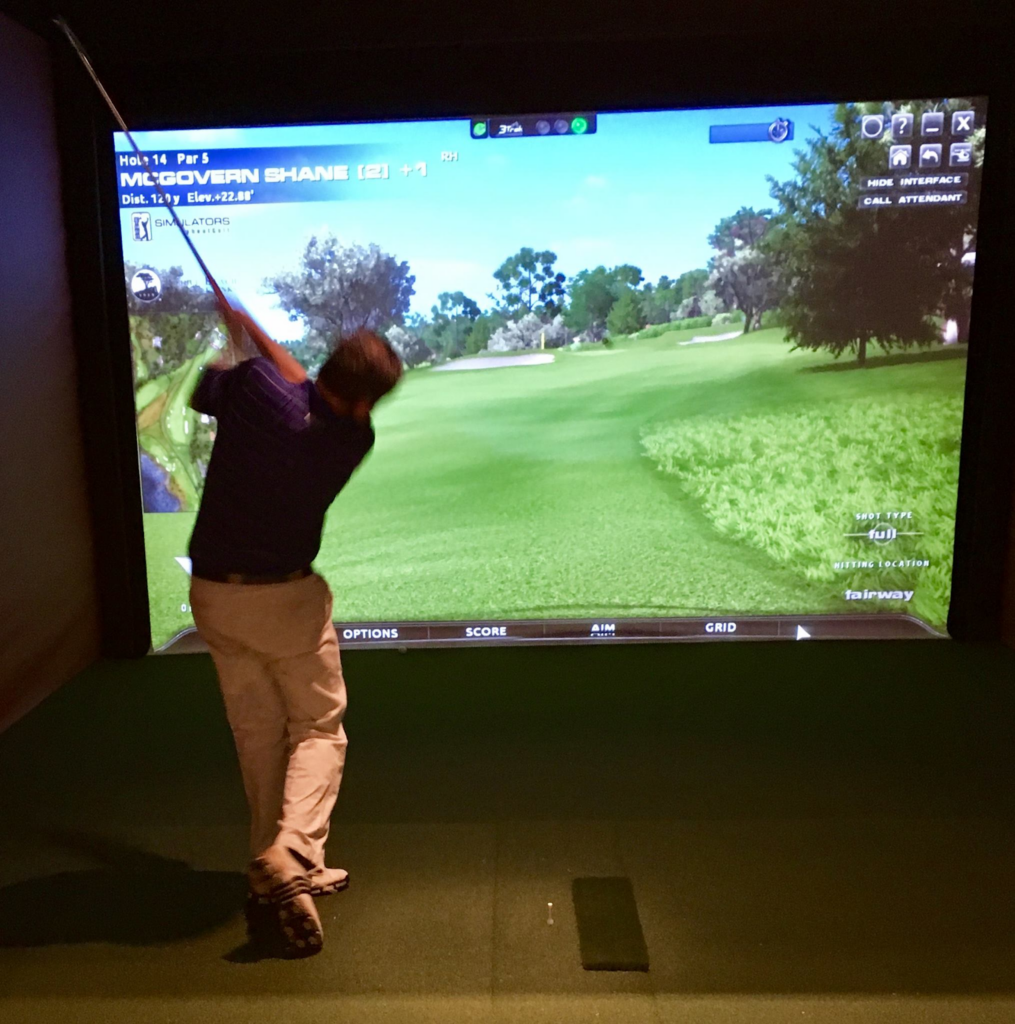 A man playing simulator golf; one of the best things to do this summer