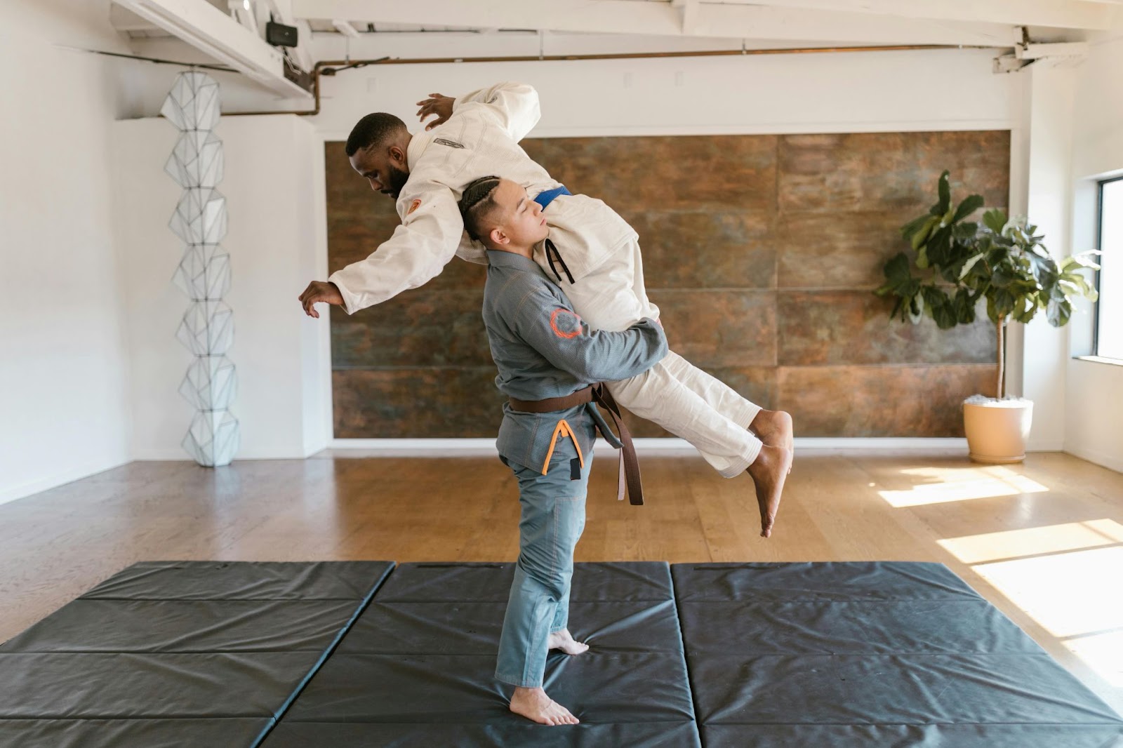 A martial arts students lifts his instructor during a training session