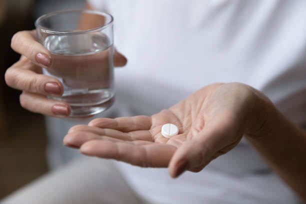 A woman in midlife holding a glass of water and a supplement, symbolizing natural solutions for managing perimenopause symptoms.