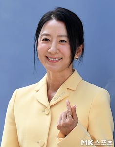 This contains an image of  Kim Hee Ae's  on a yellow dress with her smiling 