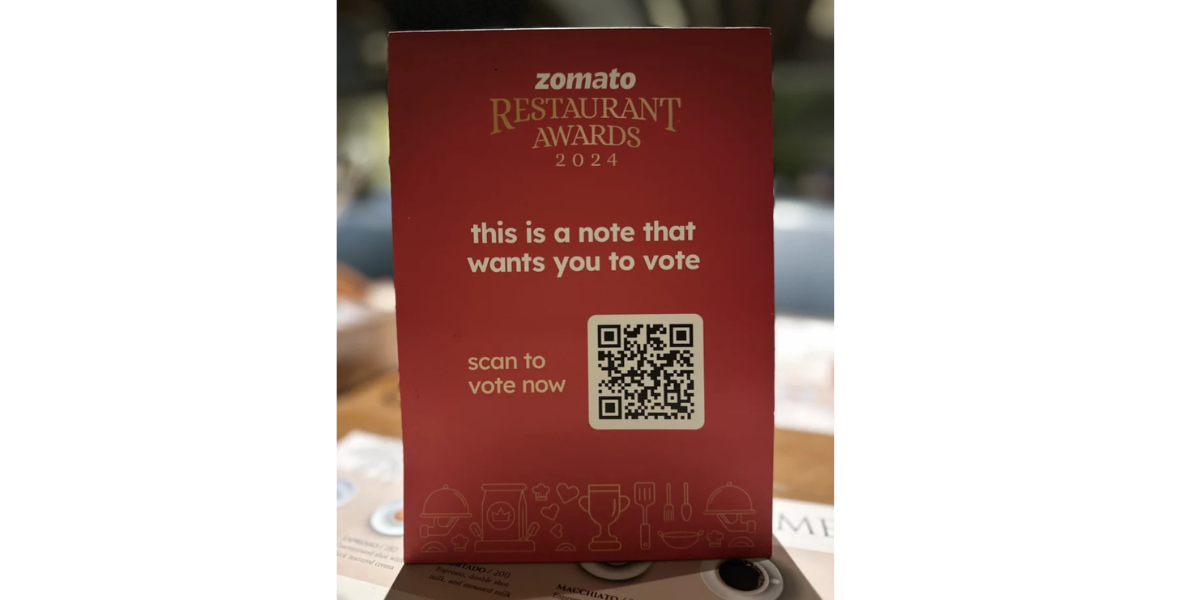 A QR Code sticker on Zomato's table tent in a restaurant.