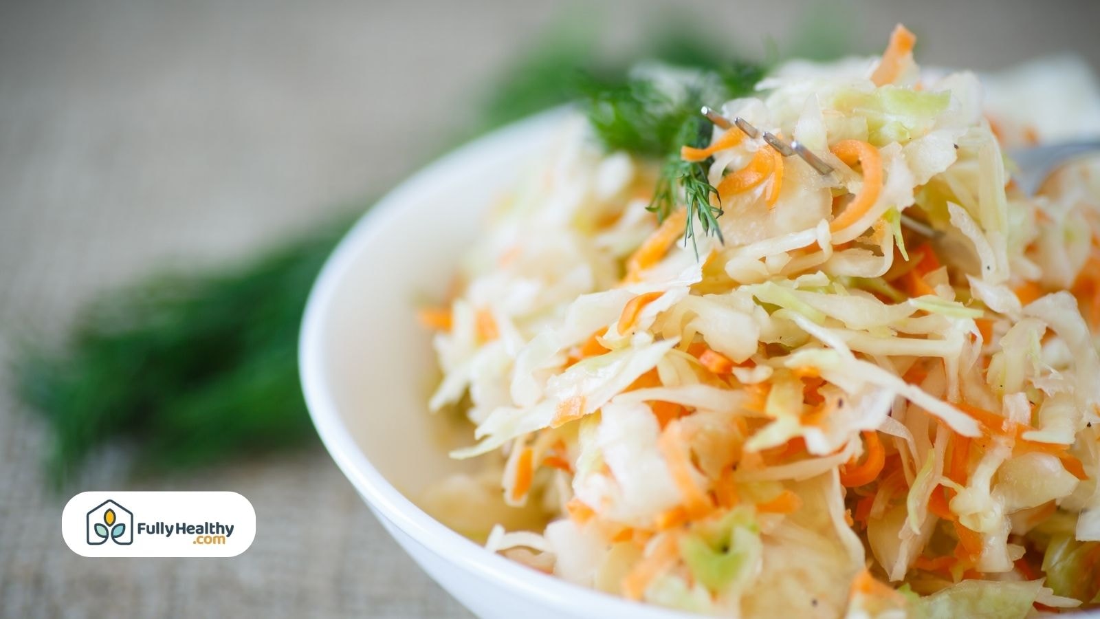 Close-up of sauerkraut with carrots and dill in white bowl