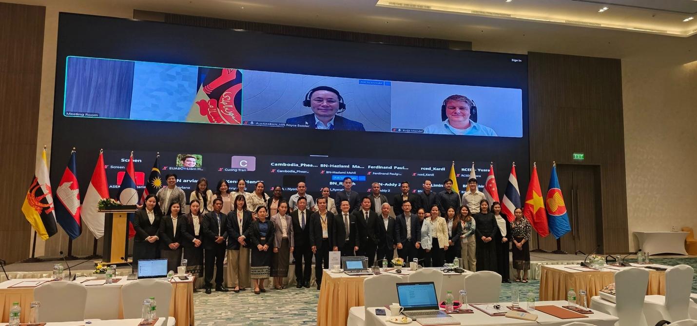 A group of people standing in front of a large screen

Description automatically generated