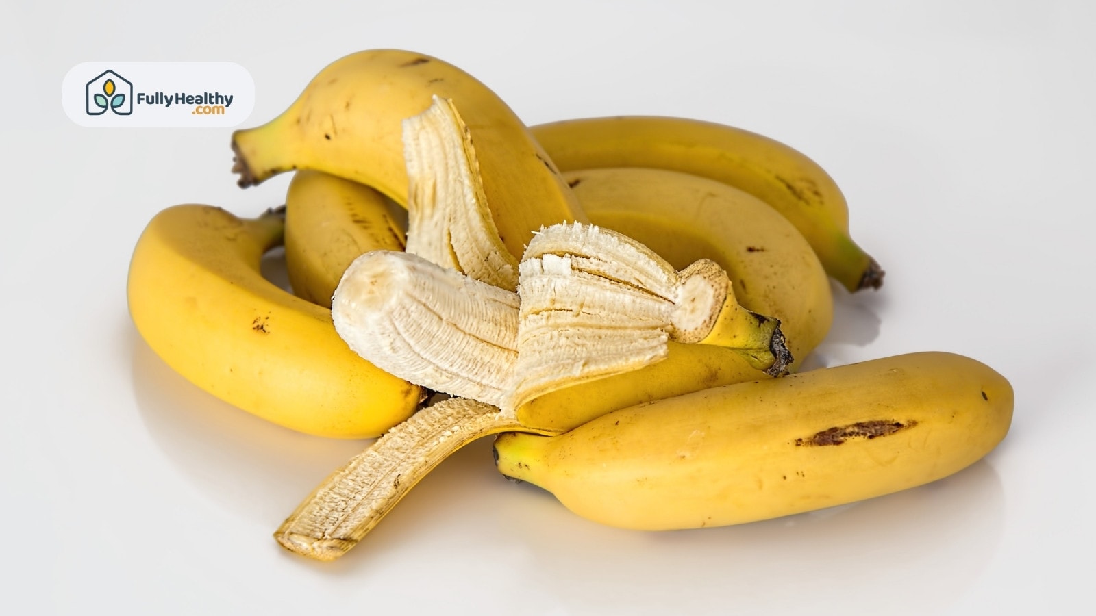 Partially peeled banana on top of whole bananas