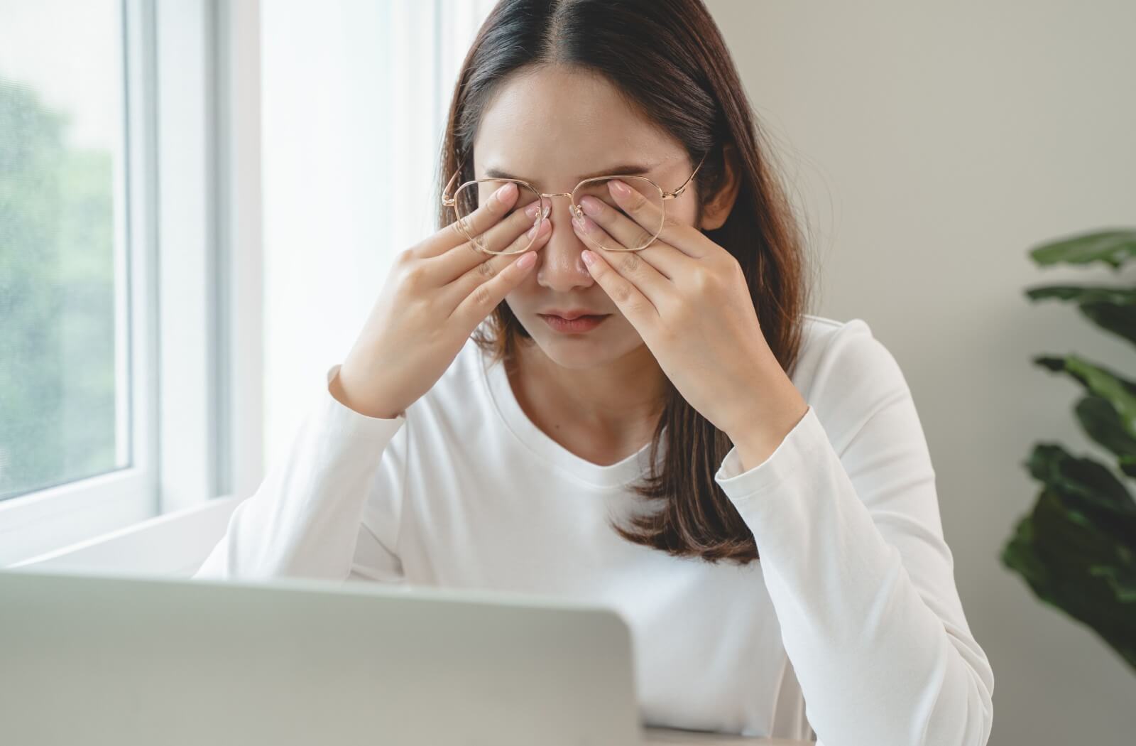 A dry eye sufferer rubbing their eyes after spending a lot of time looking at a computer screen