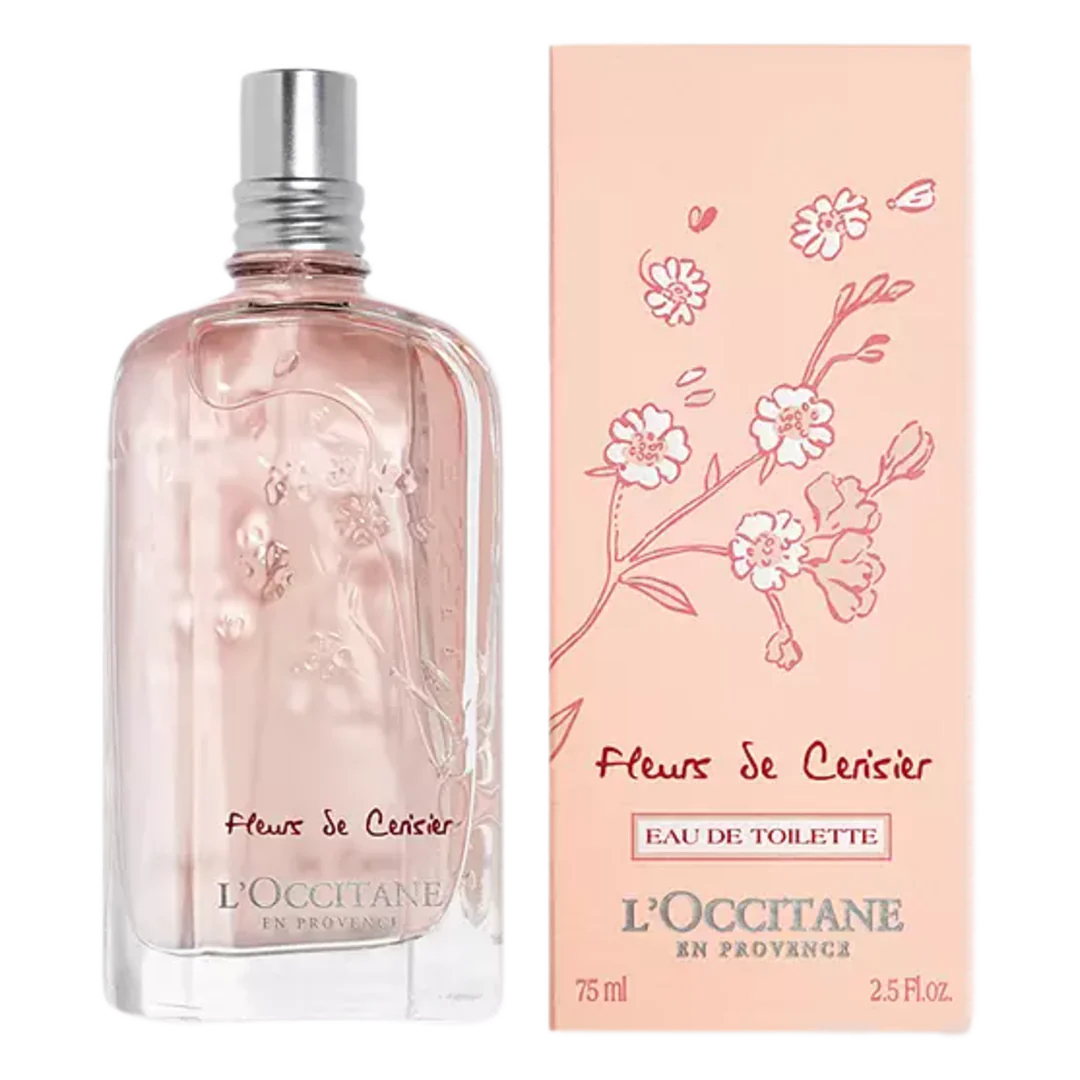 A pink-tinted glass bottle of L'Occitane Fleurs de Cerisier perfume, next to its soft pink packaging decorated with cherry blossom illustrations.