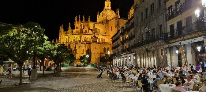 A group of people sitting at tables outside a buildingDescription automatically generated