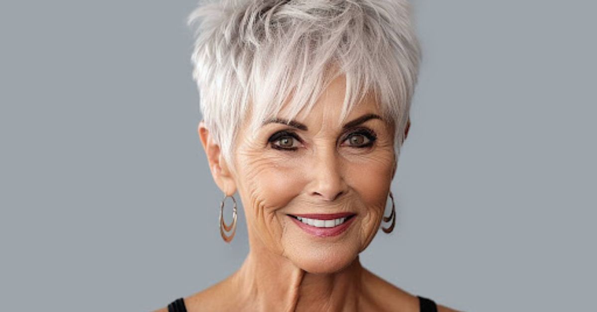 A woman with short white hair, smiling, showcasing a stylish Textured Pixie with Bangs hairstyle.