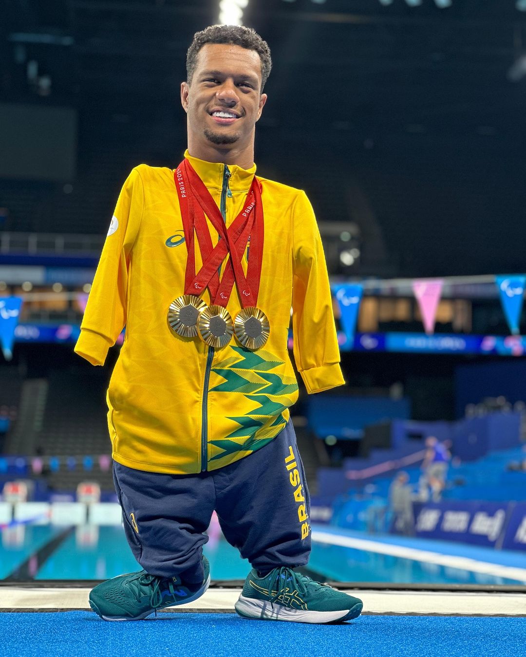 Gabrielzinho de pé com suas três medalhas conquistadas nas Paralimpíadas de Paris em 2024 no peito