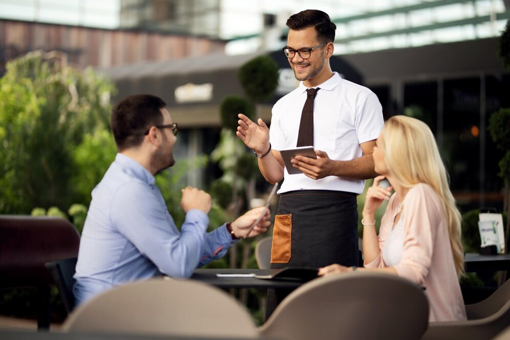 A coupld interacting happily with the restaurant staff.