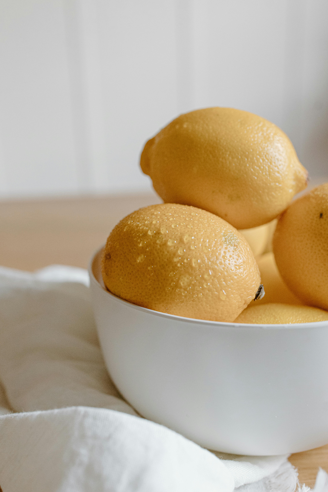 A bowl of lemons on a white cloth
