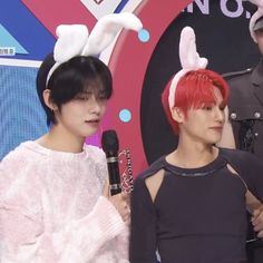 This contains an image of Wooyoung and Yeonjun  standing next to each other with bunny ears on their head and one person holding a microphone