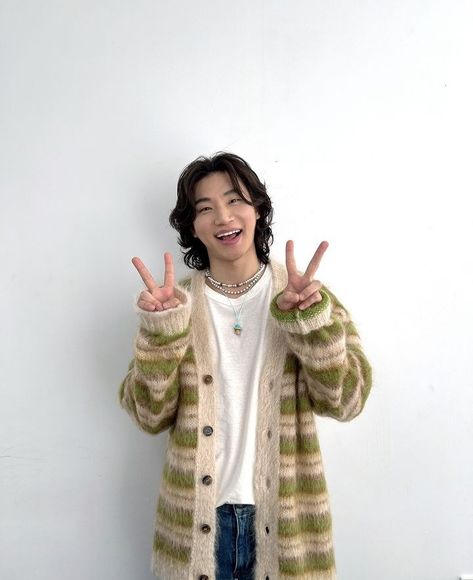 This contain BIGBANG members Daesung  standing in front of a white wall making the peace sign