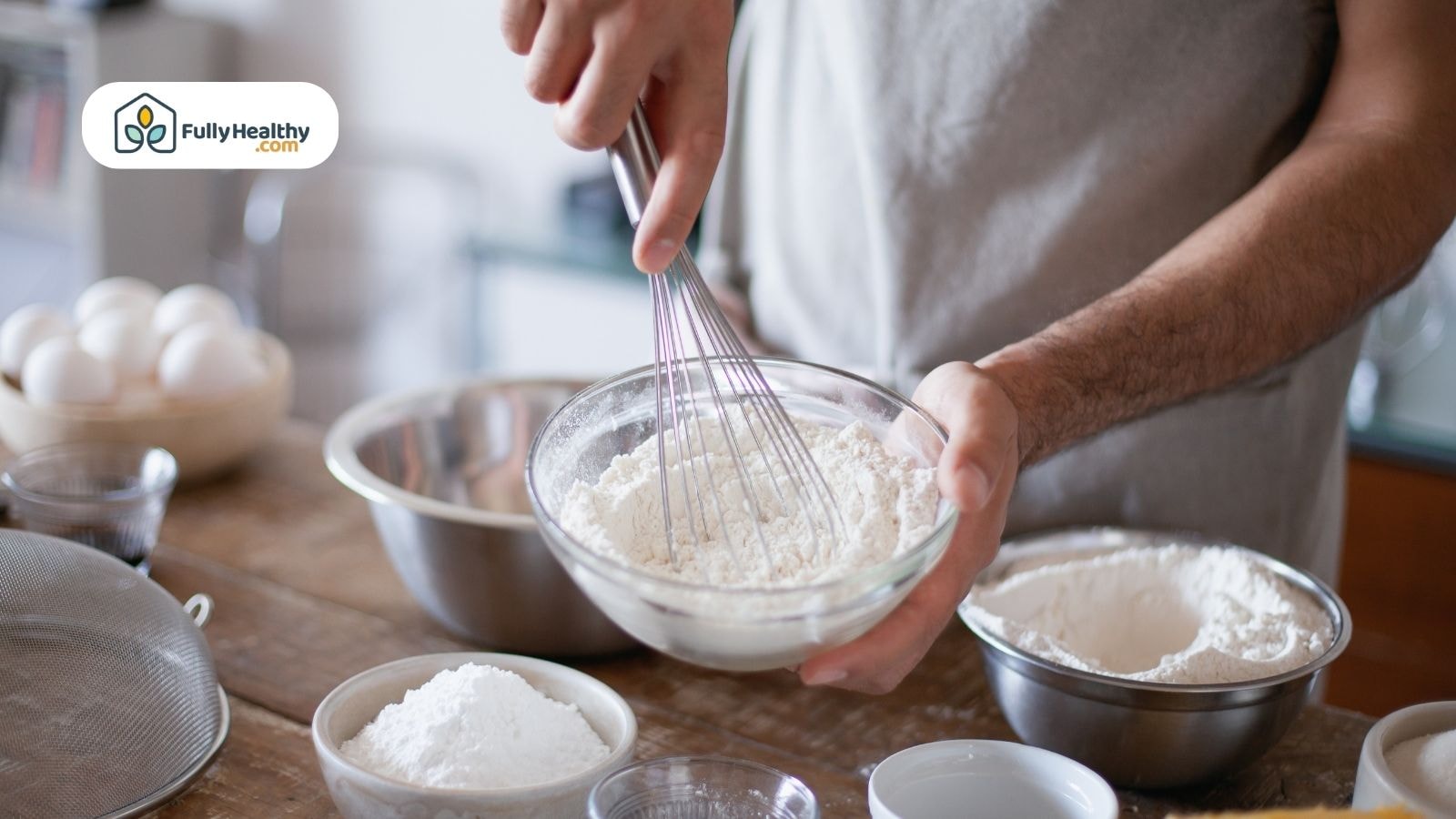 Man whisking in a glass bowl with dry baking ingredients