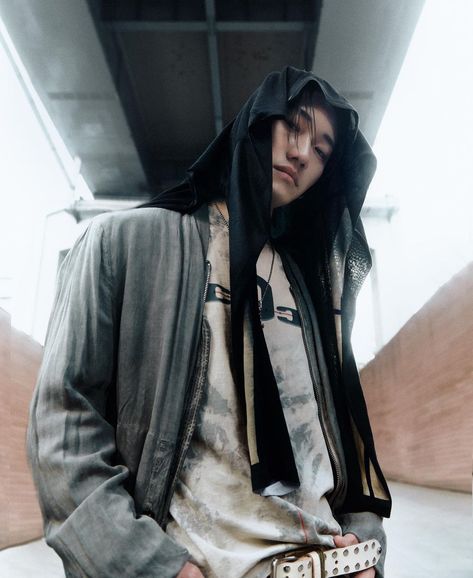 This contain DPR Artic wearing a hoodie and holding his hands in his pockets while standing under a bridge