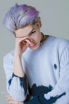 A picture of Taeyong  wearing a light sky blue sweeter and a colour hair with his hand on his face