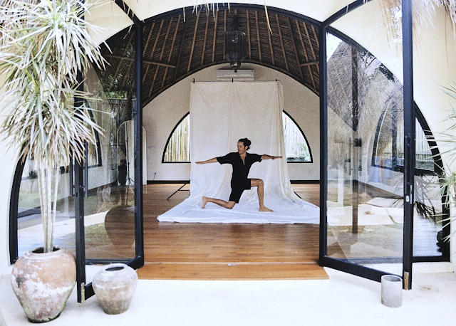 A woman practicing yoga in a luxurious, serene studio with soft lighting and elegant decor, embodying relaxation and mindfulness